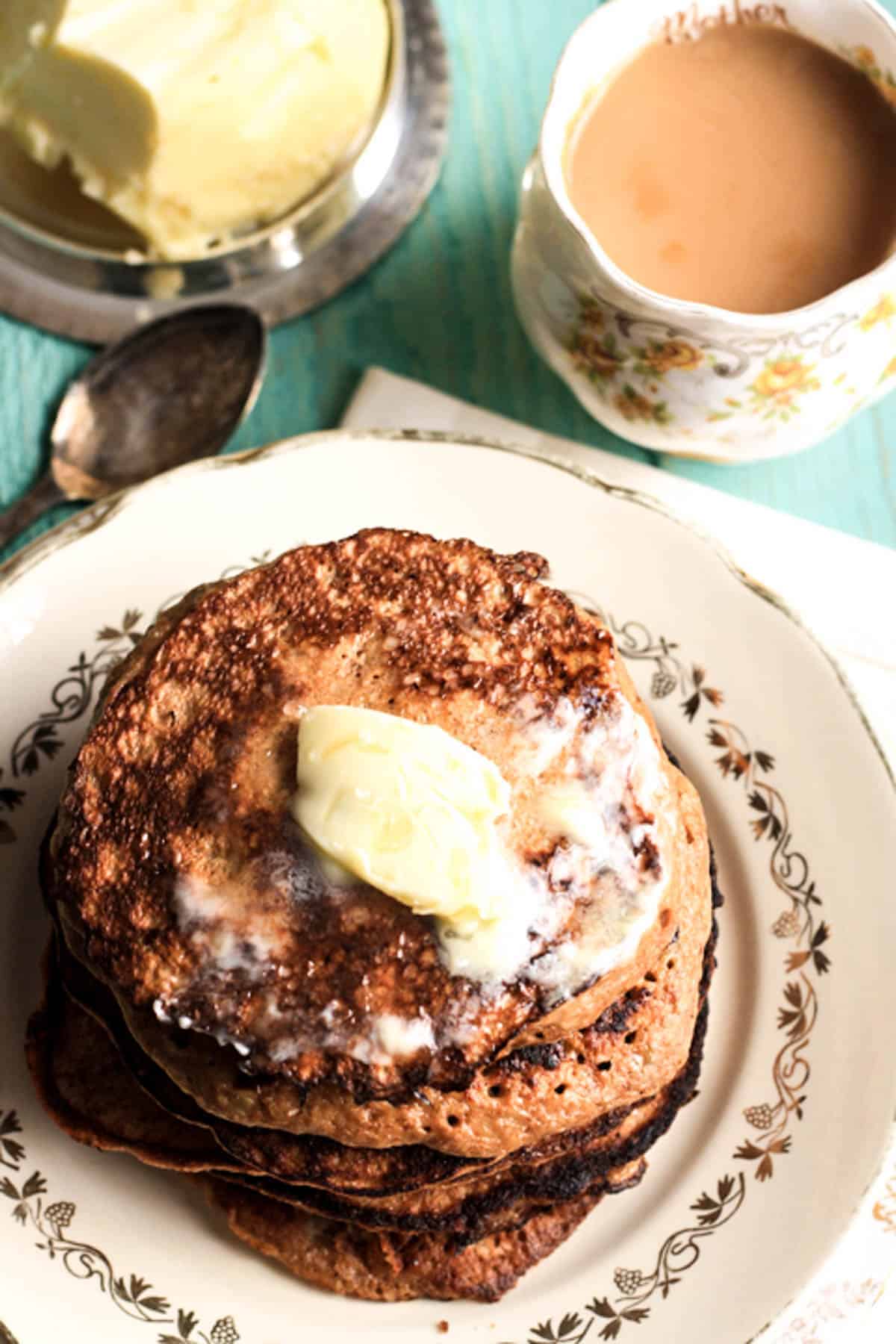 A stack of Banana and Walnut Pancakes on a plate with melted butter