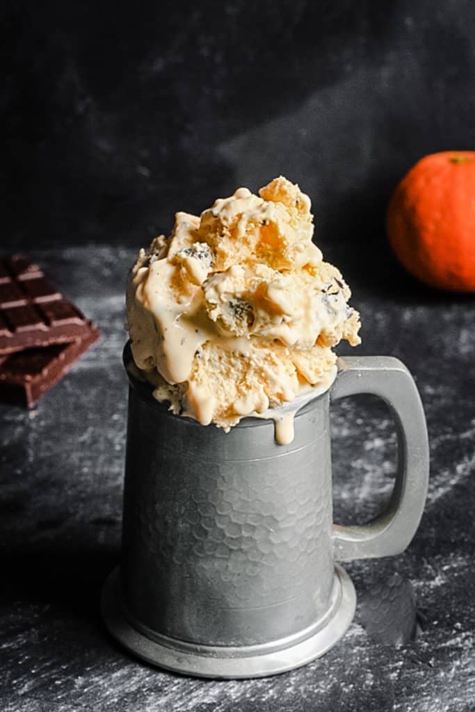 A close up of ice cream in a tankard in front of orange and chocolate
