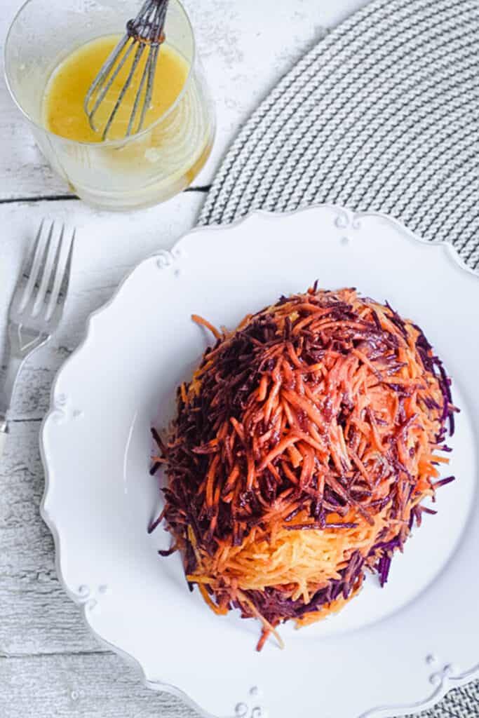 A plate of grated carrot salad next to dressing