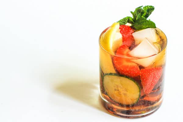 A glass of Homemade Pimms filled with fruit and ice
