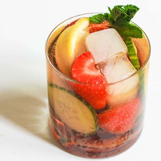 A glass of Homemade Pimms filled with fruit and ice