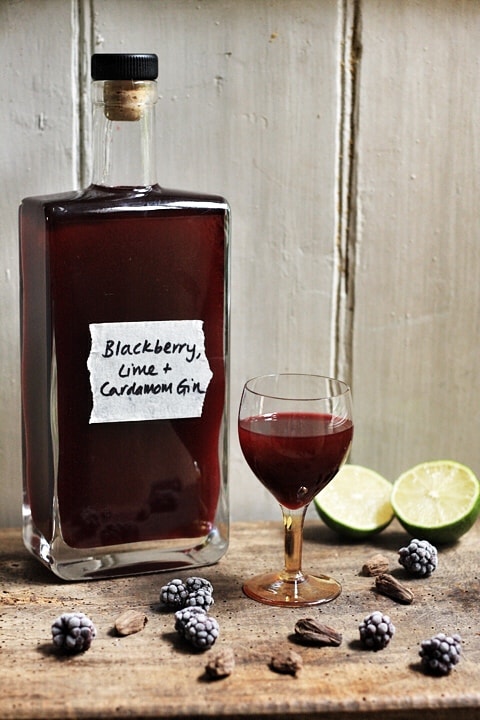 A bottle of blackberry liqueur and a glass of blackberry liqueur on a table