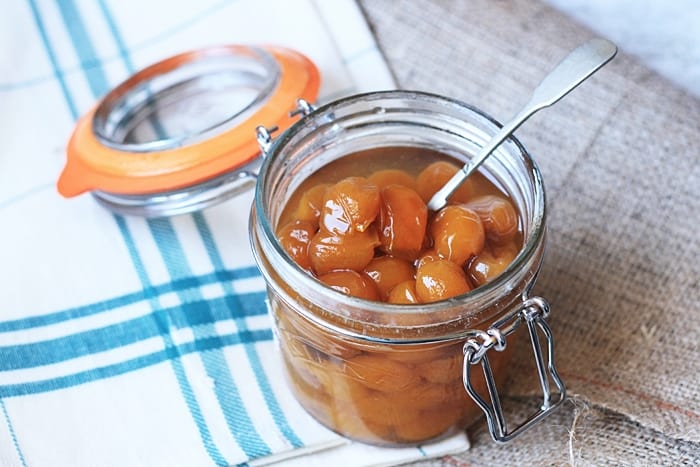 A jar of pickled mirabelles on a table