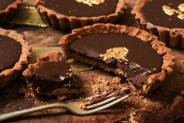 A half eaten piece of chocolate tart on a plate