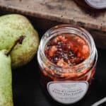 Pear jam in a jar next to pears