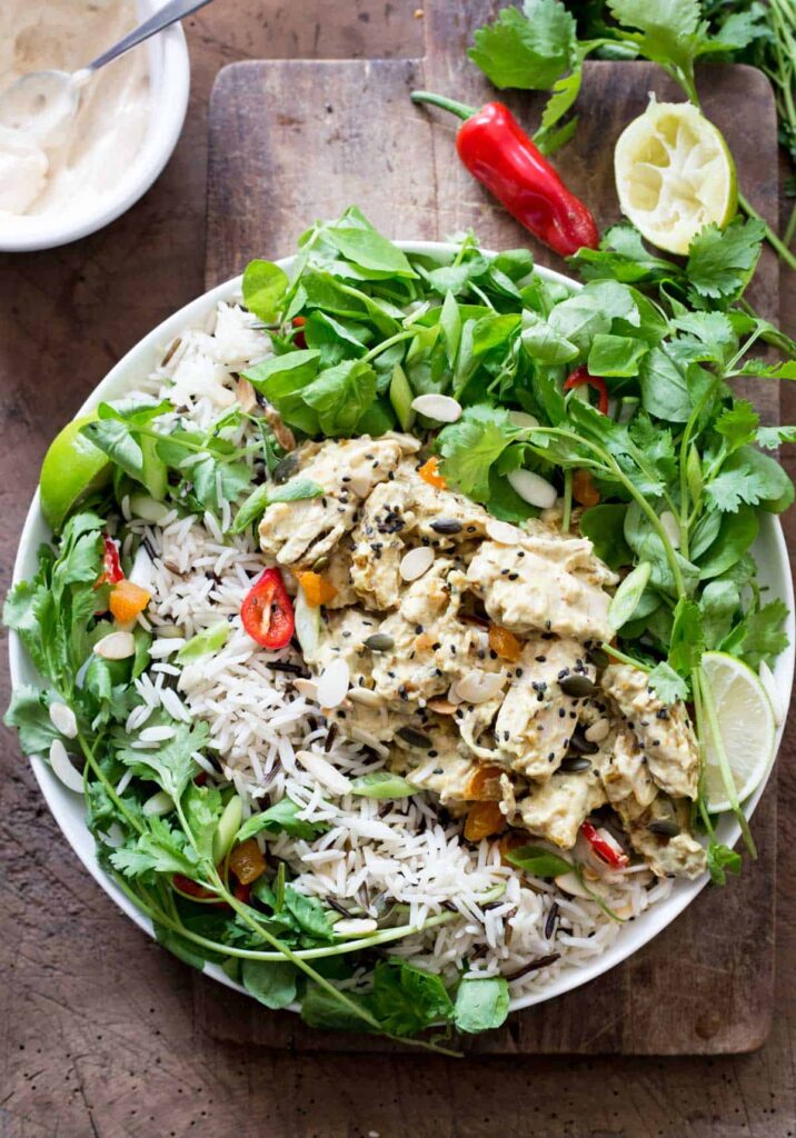 A bowl of Coronation Chicken Salad on a wooden board