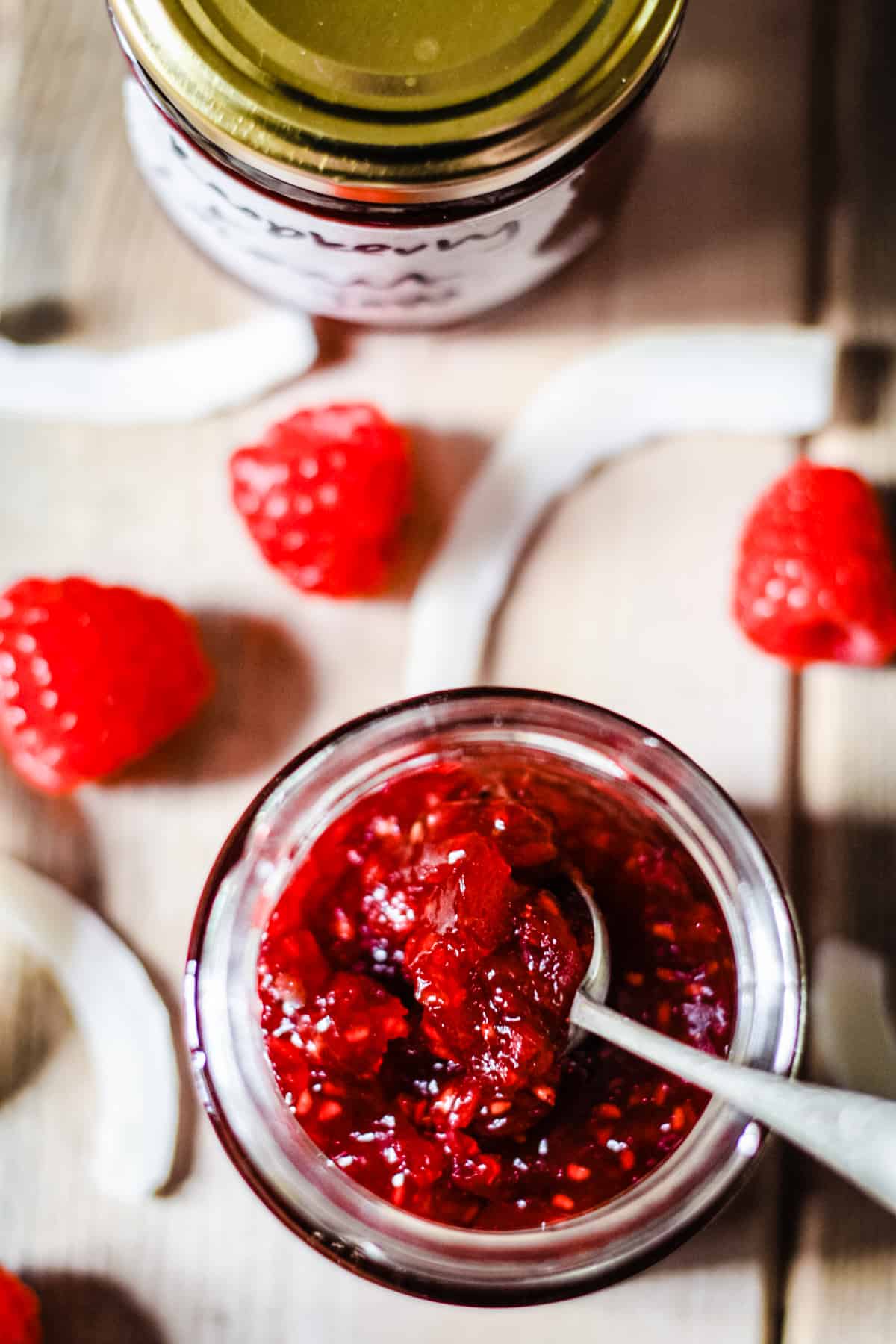 overview of a jar of raspberry coconut jam with a spoon in it