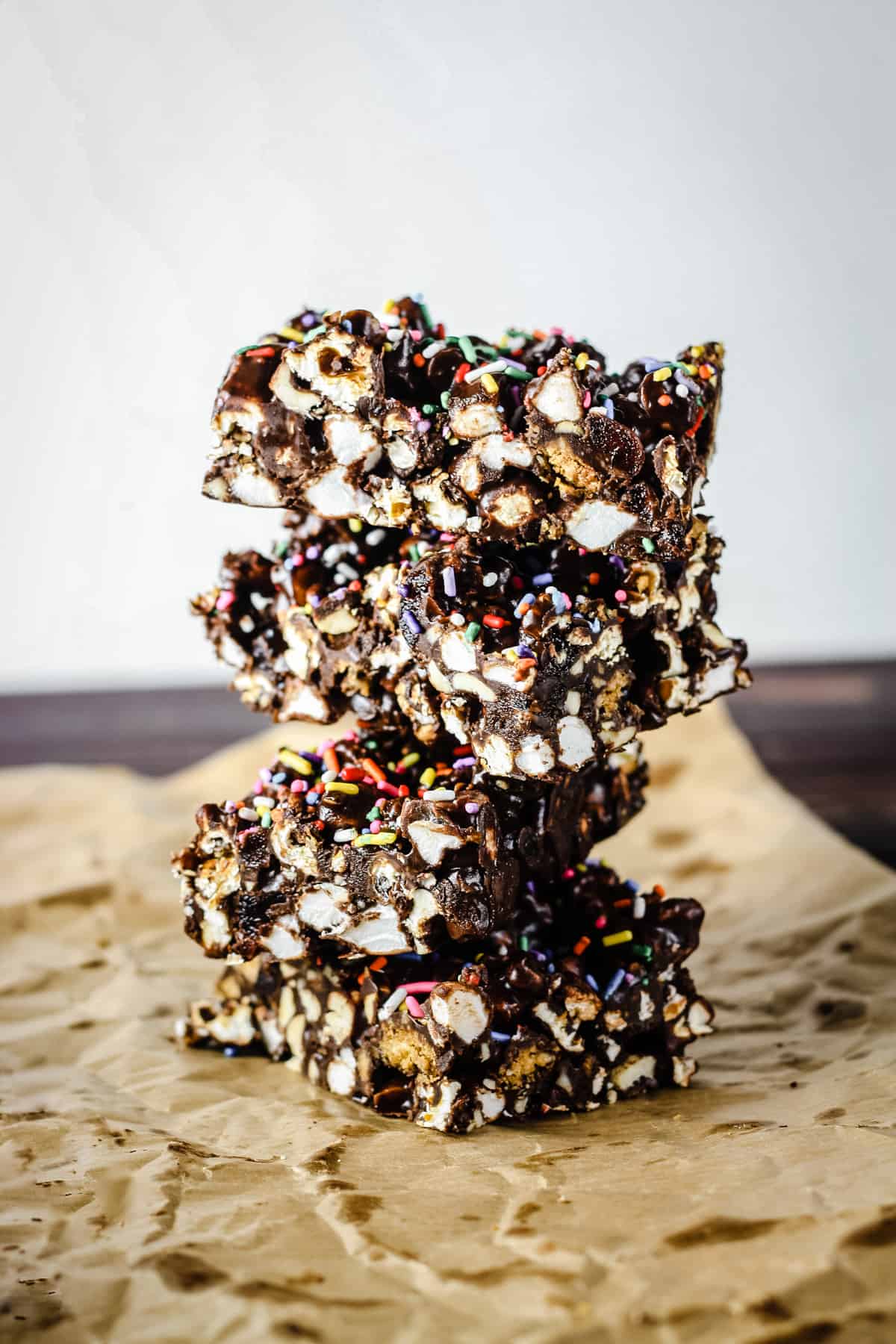 side view of stack of Ultimate Popcorn Rocky Road bars on baking parchment on wooden board