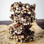 side view of stack of Ultimate Popcorn Rocky Road bars on baking parchment on wooden board