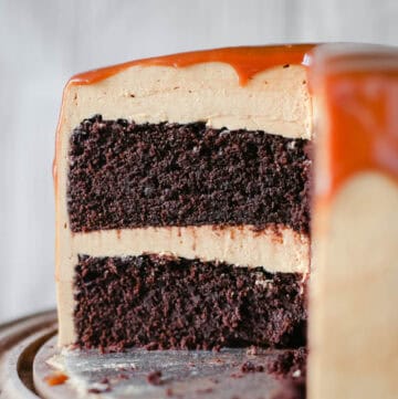 salted caramel chocolate cake on a wooden cake stand.