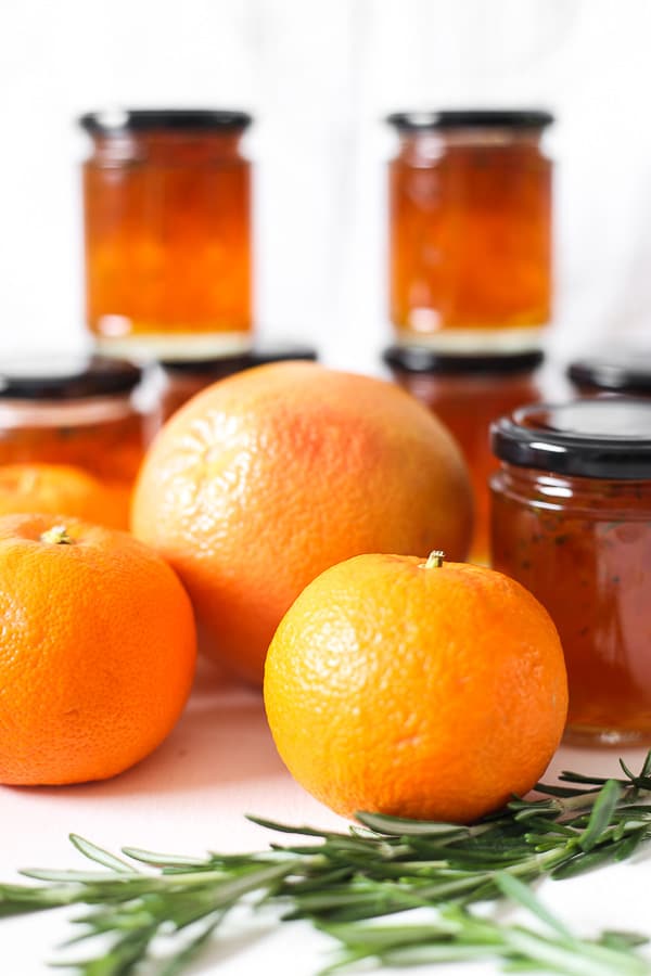 citrus fruits on a table in front of jars of marmalade