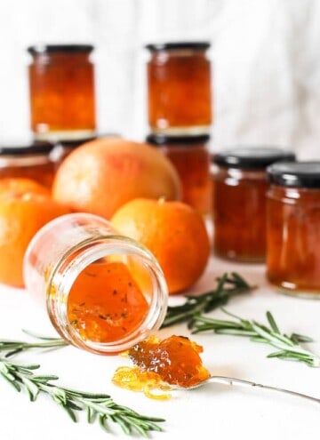 jar of marmalade on the side. jars of marmalade behind. spoon of marmalade in front.