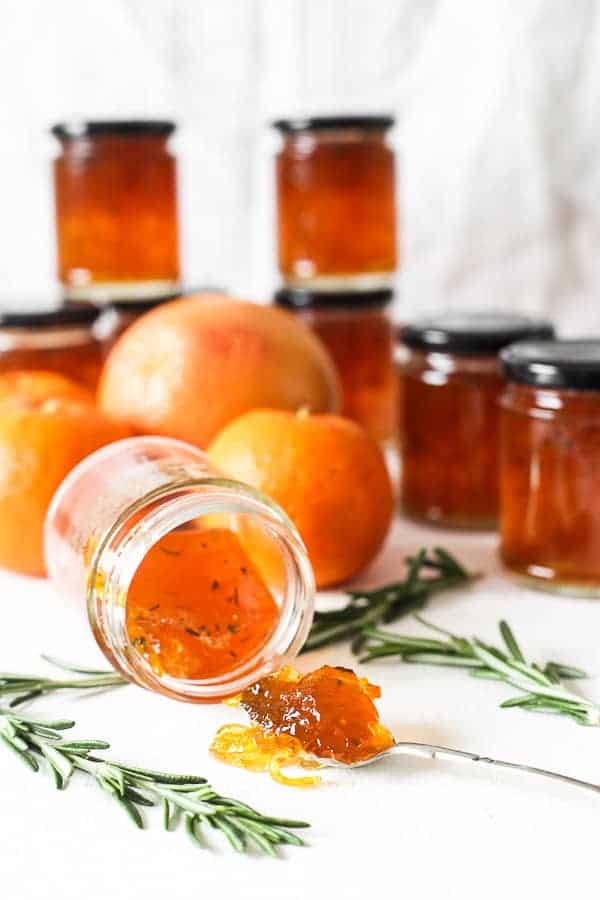 jar of marmalade on the side. jars of marmalade behind. spoon of marmalade in front.