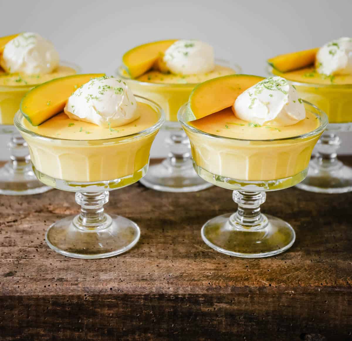 glass bowls of mango pudding on a wooden table
