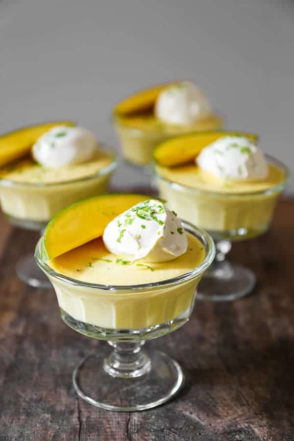 glass bowls of mango pudding on a wooden table
