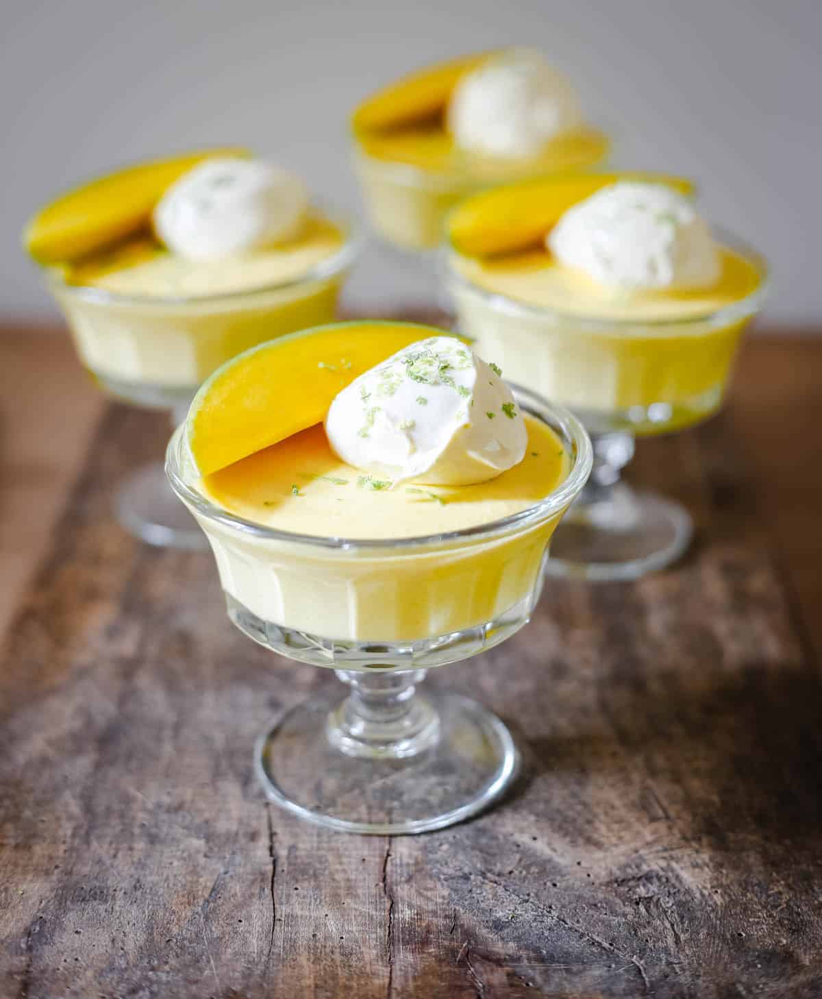 glass bowls of mango pudding on a wooden table