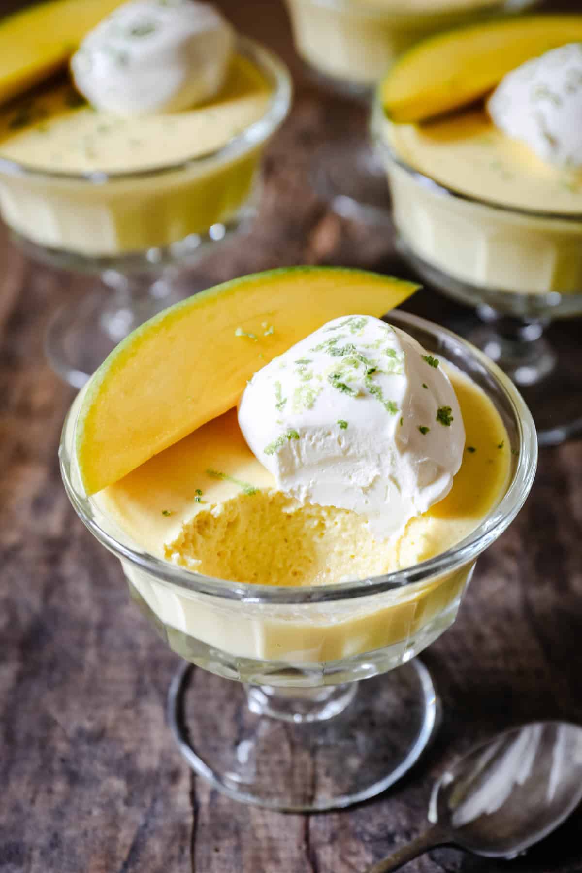 A bowl of mango pudding with spoon ful taken out