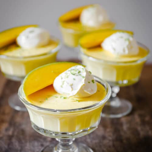 glass bowls of mango pudding on a wooden table