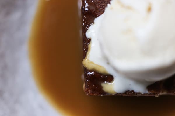 A piece of cake and ice cream in a bowl with toffee sauce