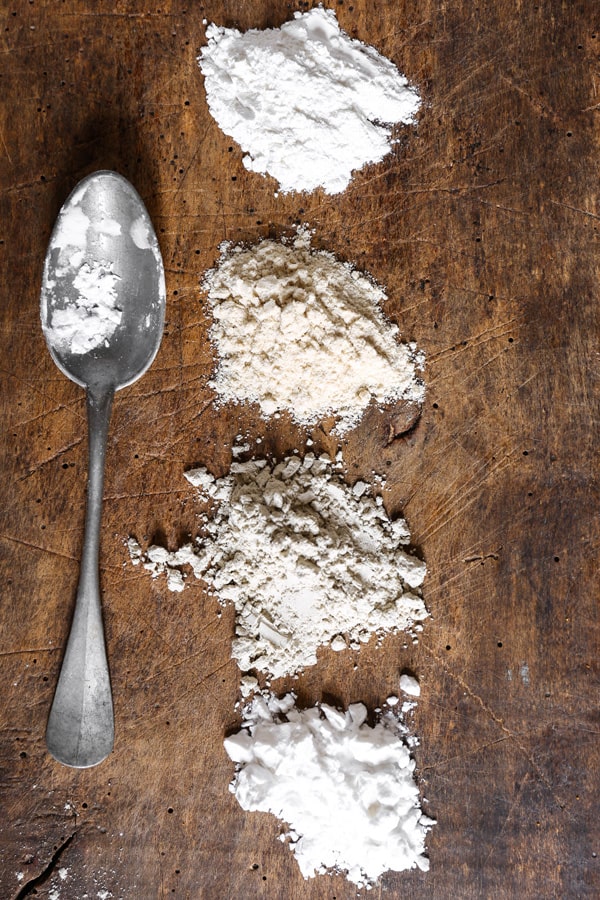 Little heaps of different gluten-free flours on a wooden board