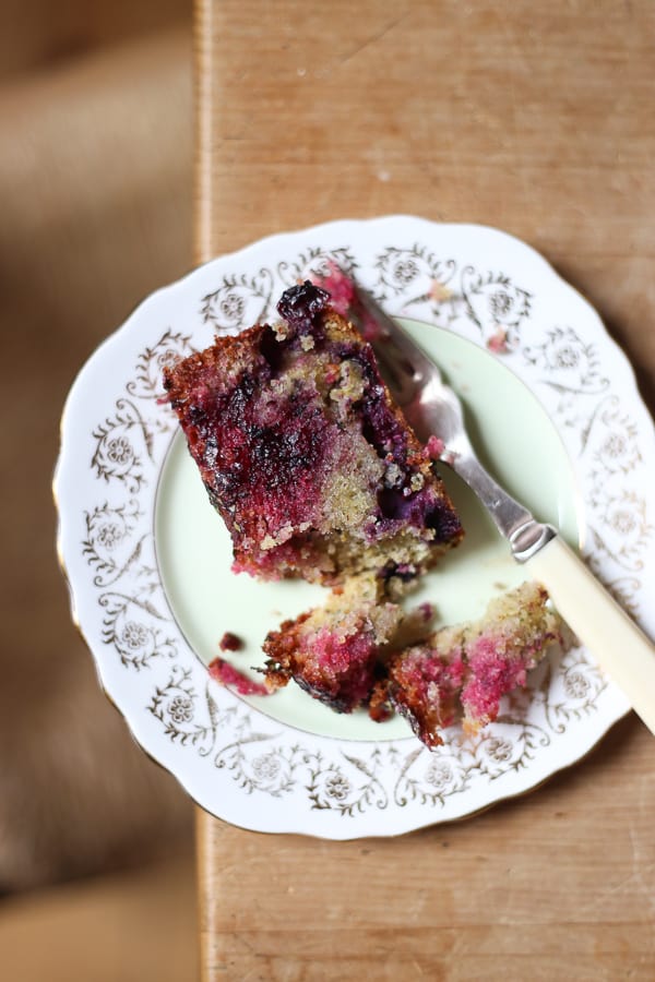 Blueberry Basil Lemon Drizzle cake on a plate on a wooden table