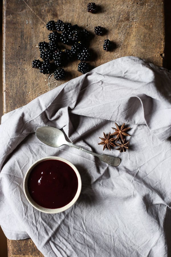 Blackberry Hoisin Sauce in bowl with spoon on tablecloth with star anise