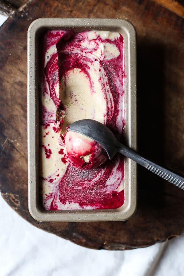 Blackberry Ripple Ice Cream in tin on wooden board with scoop of ice cream taken out