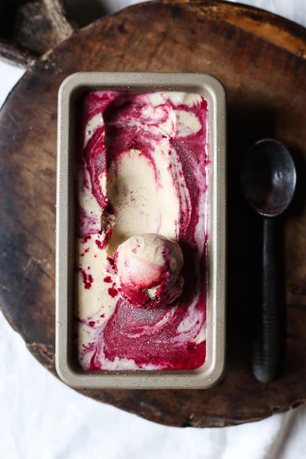 Blackberry Ripple Ice Cream in tin on wooden board with scoop of ice cream taken out