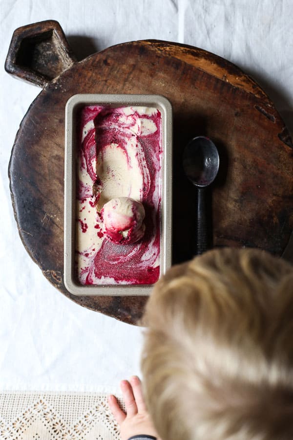 Blackberry Ripple Ice Cream in tin on wooden board with scoop of ice cream taken out