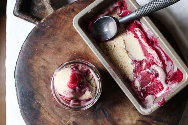 Blackberry Ripple Ice Cream in tin on wooden board with scoop of ice cream taken out in a glass