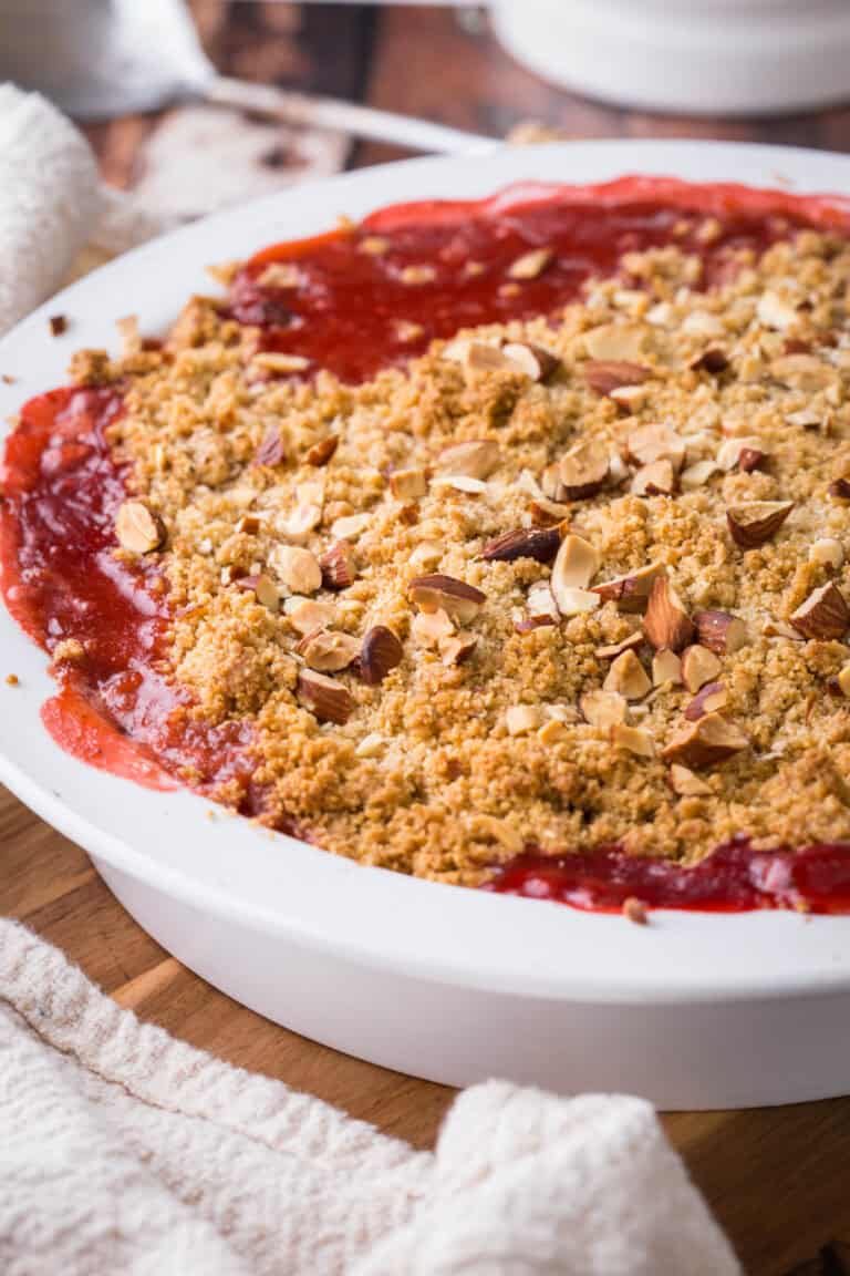 Dish of Strawberry Gooseberry Crumble with fruit bubbling beneath the crumble topping.