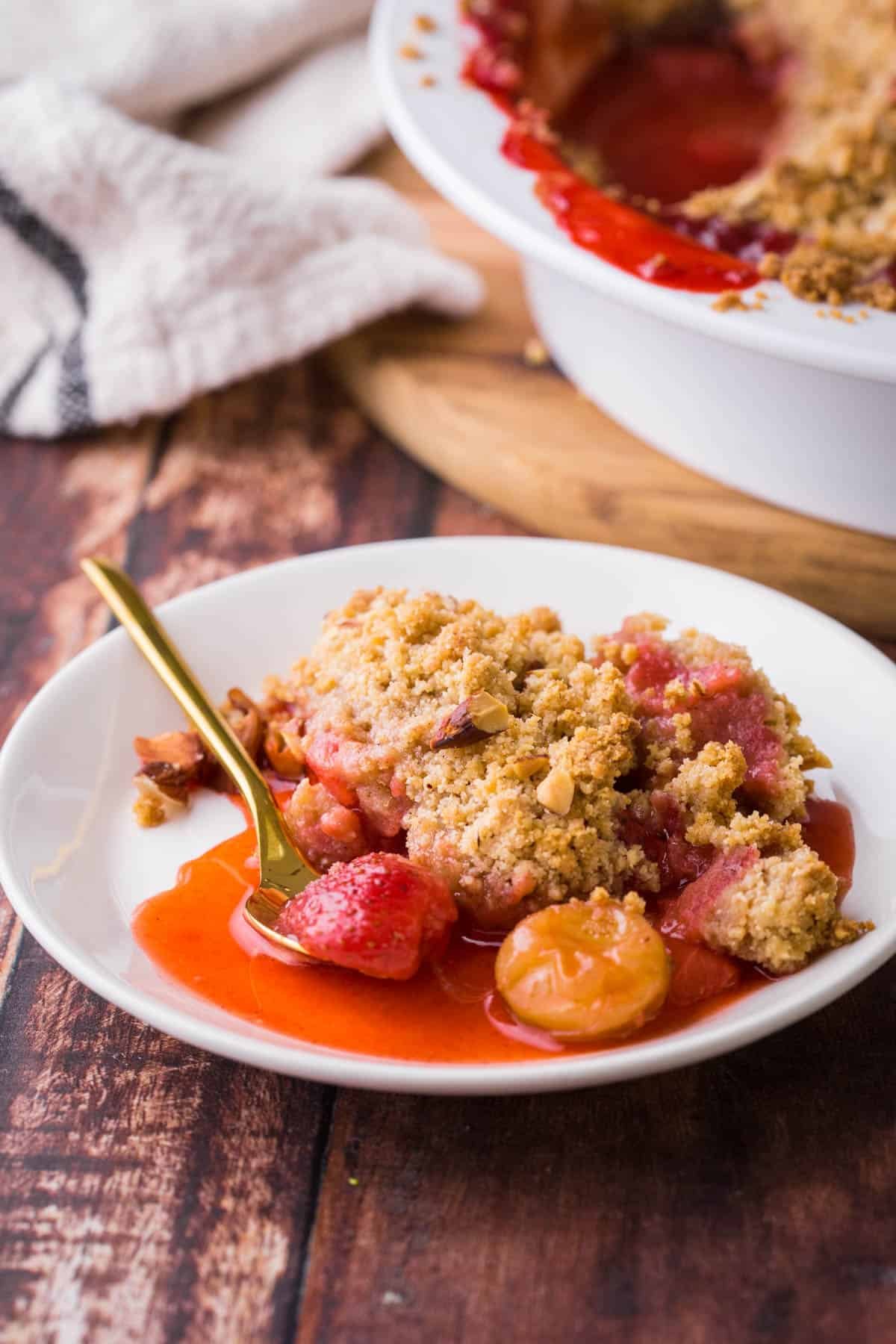 Overhead images of a dish of Strawberry Gooseberry Crumble with a spoon