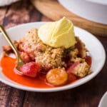 strawberry gooseberry crumble on plate with ice cream on top.