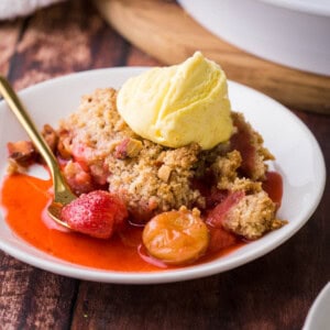 strawberry gooseberry crumble on plate with ice cream on top.