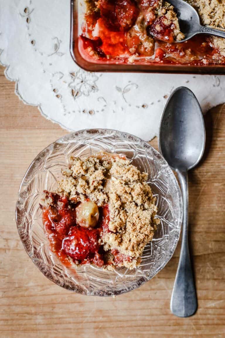 Overhead image of a bowl of Strawberry Gooseberry Crumble with a spoon