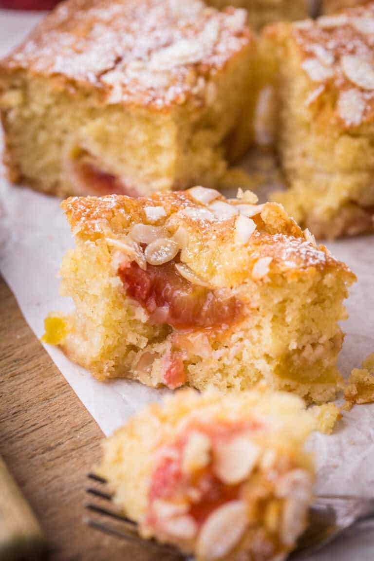 A piece of Gluten-Free Plum Almond Cake with a forkful taken out showing juicy plum filling encased in light soft fluffy moist cake.