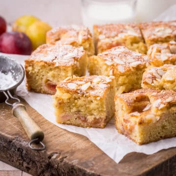 Gluten-Free Plum Cake sliced into squares and presented on wooden board.