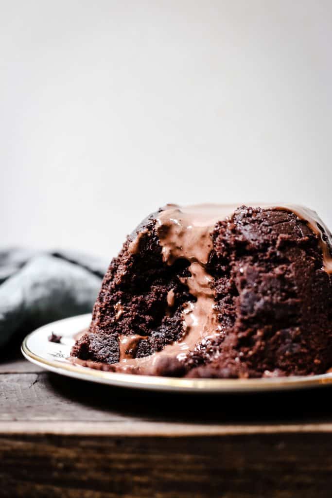 Steamed Chocolate Sponge Pudding with slice taken out and Chocolate Custard poured over the top