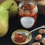 jar of jam next to pears and cobnuts with spoon of jam in a lid