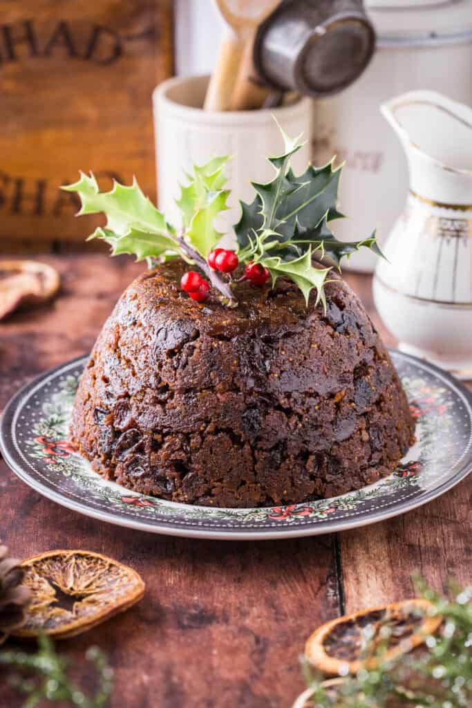 Christmas Pudding on a plate with a sprig of holly on top.