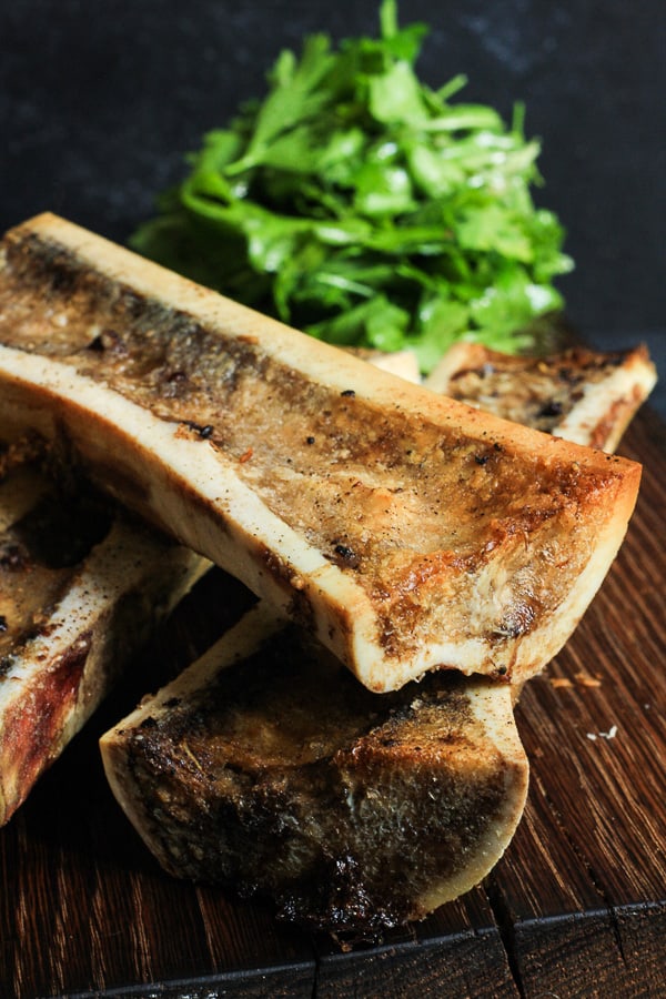 A close up of roasted bone marrow next to parsley