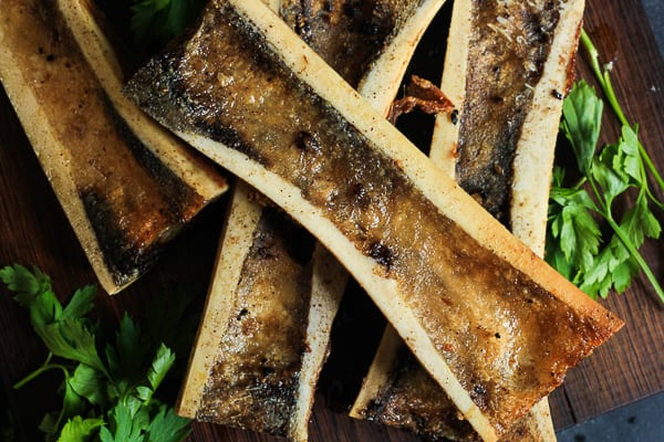 A close up of roasted bone marrow next to parsley