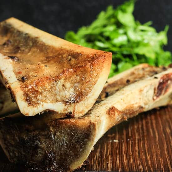 A close up of roasted bone marrow next to parsley