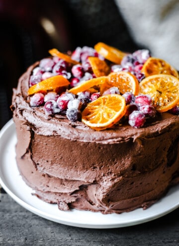 Chocolate Cranberry Clementine Cake on a white plate on a wooden board