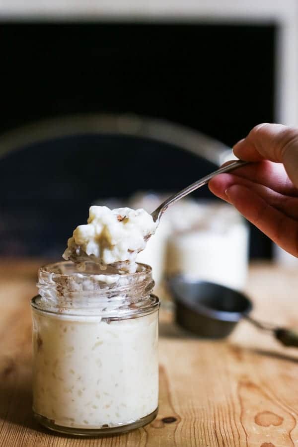 hand holding spoon lifting out rice pudding from a jar