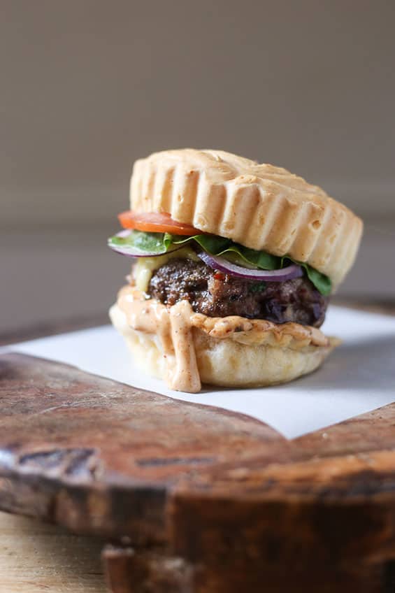 A close up of a burger sitting on top of a wooden table