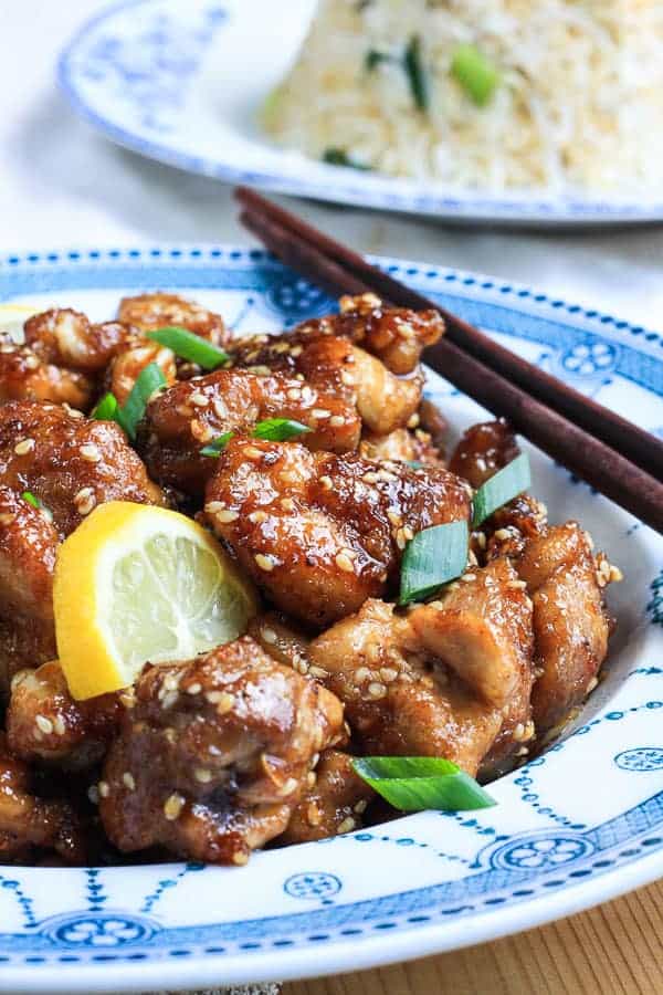 A bowl of lemon honey sesame chicken with chopsticks on a table