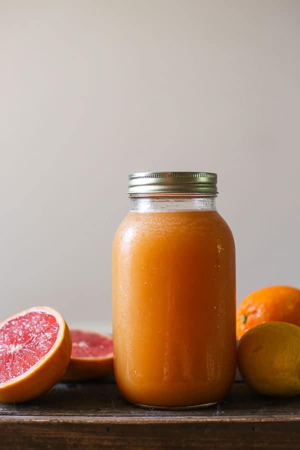 A jar of shrub surrounded by citrus fruit