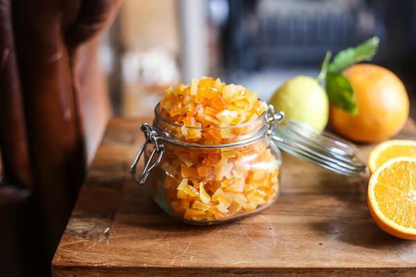 Homemade Mixed Peel in a jar on a table surrounded by citrus fruits