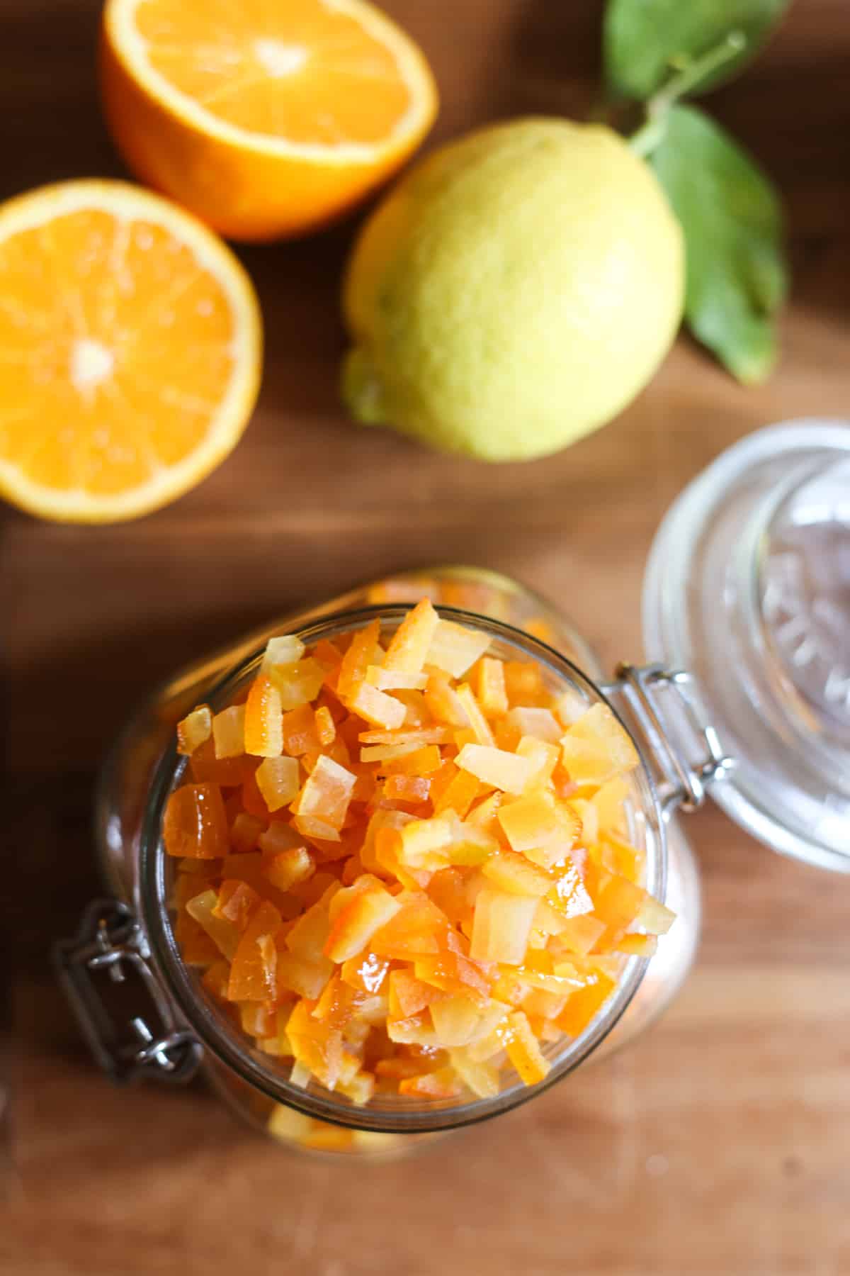 Close up of Homemade Mixed Peel in a jar surrounded by citrus fruits